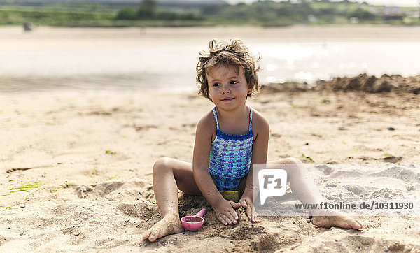 Portrait of smiling little girl wearing swim suit playing on the beach