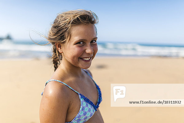 Porträt eines lächelnden Mädchens im Bikini-Top am Strand