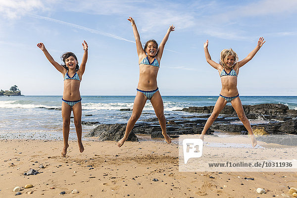 Spanien  Colunga  drei Mädchen  die am Strand in die Luft springen