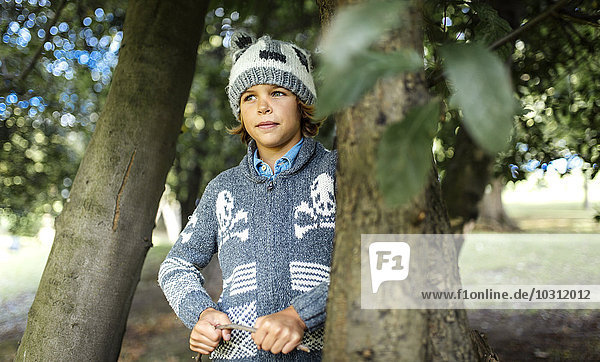 Porträt eines Jungen in Herbstmode zwischen zwei Bäumen stehend