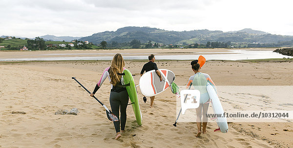 Spanien  Asturien  Villaviciosa  drei Stehpaddler auf dem Weg zum Wasser