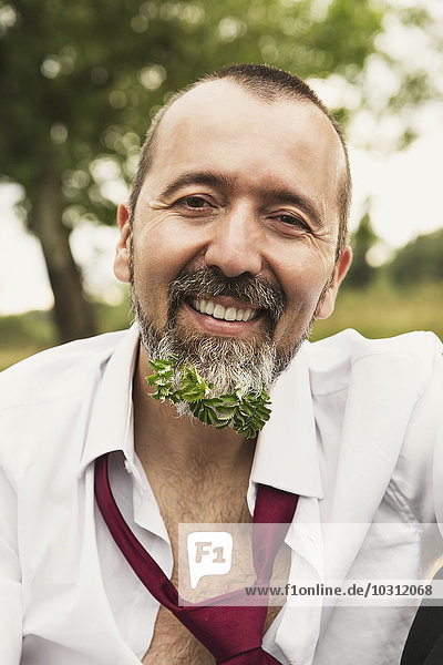 Porträt eines lächelnden Geschäftsmannes mit Pflanze im Bart