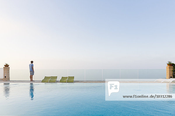 Spanien  Balearen  Mallorca  ein Teenager steht auf einer Glasschiene am Swimmingpool.