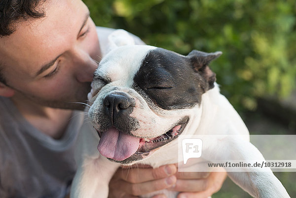 Mann küsst seine französische Bulldogge