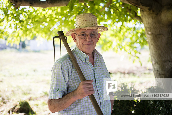 Porträt eines älteren Mannes mit Hacke auf der Schulter