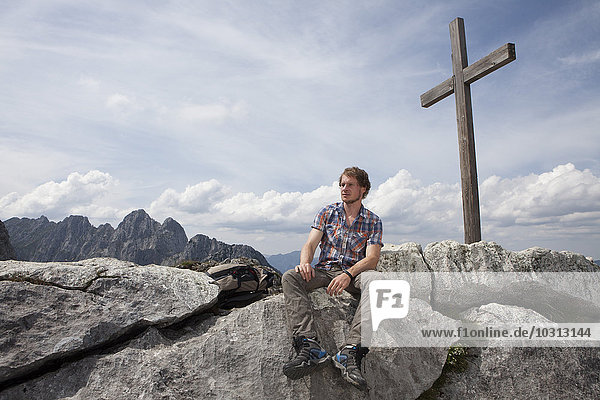 Germany  Bavaria  Osterfelderkopf  man sitting at summit cross