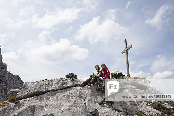 Deutschland  Bayern  Osterfelderkopf  Paar ruht am Gipfelkreuz