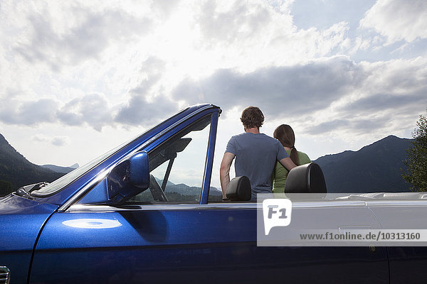 Germany  Bavaria  couple next to convertible looking at view