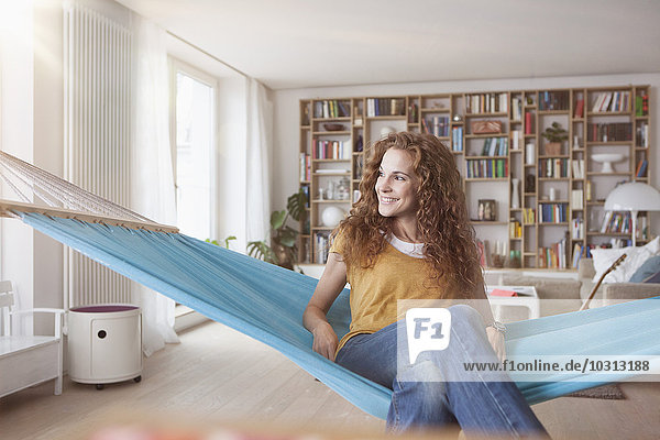 Lächelnde Frau zu Hause in der Hängematte sitzend