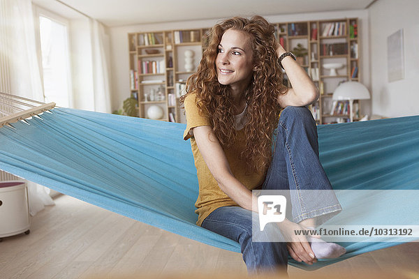 Lächelnde Frau zu Hause in der Hängematte sitzend