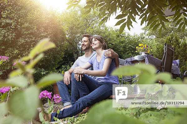 Smiling couple sitting on garden terrace