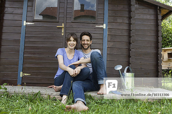 Lächelndes Paar sitzend im Gartenhaus