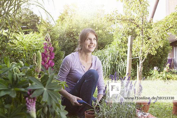 Smiling woman gardening in flowerbed