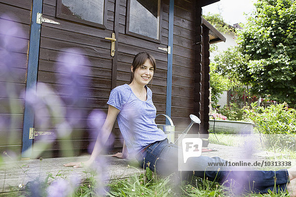 Lächelnde Frau sitzt im Gartenhäuschen