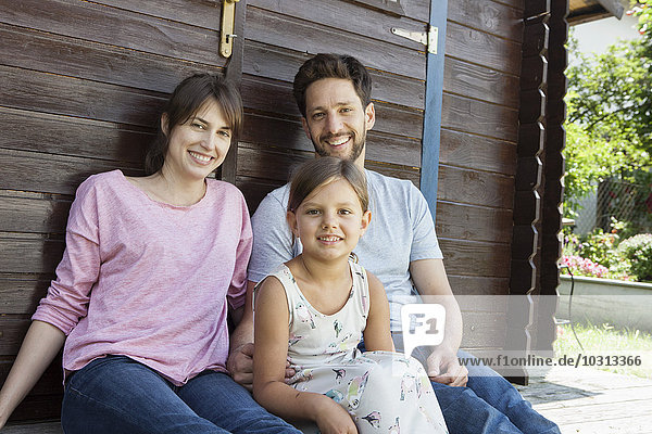 Portrait of smiling family with daughter at garden shed