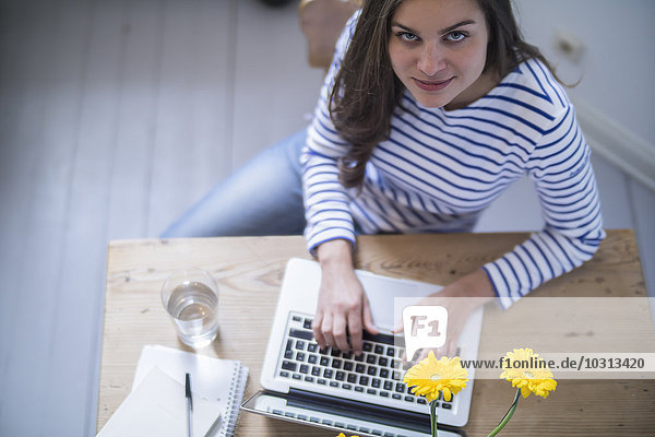 Junge Frau mit Laptop  die von zu Hause aus arbeitet