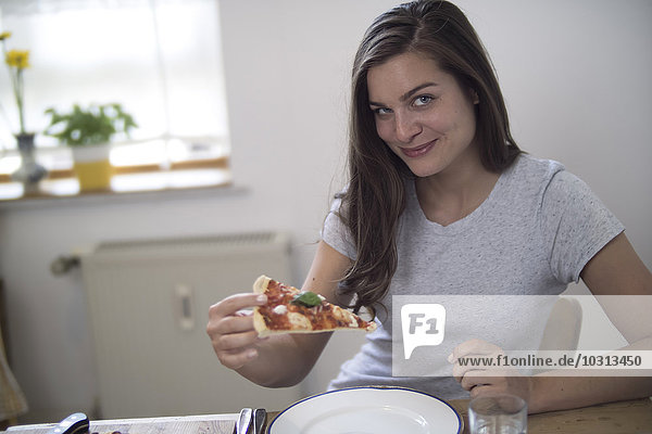 Junge Frau isst hausgemachte Pizza