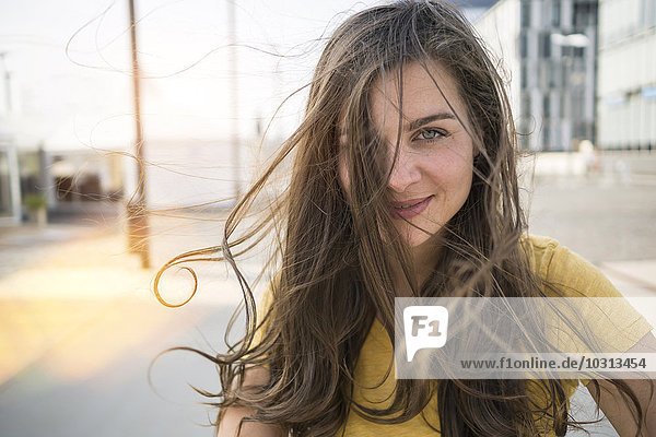 Deutschland  Köln  Porträt einer lächelnden jungen Frau mit wehendem Haar