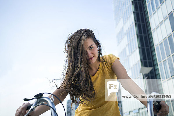 Deutschland  Köln  Porträt der lächelnden jungen Frau auf dem Fahrrad