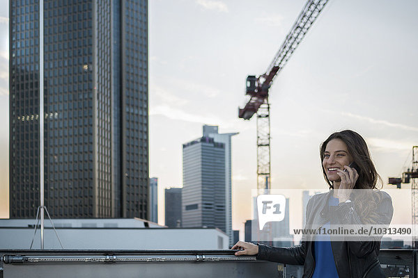 Deutschland,  Frankfurt,  Portrait einer jungen Frau beim Telefonieren mit dem Smartphone