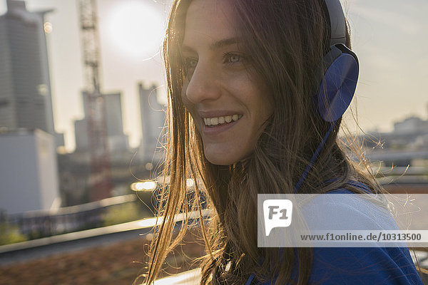 Deutschland  Frankfurt  Porträt einer lächelnden Frau  die Musik mit Kopfhörern hört.
