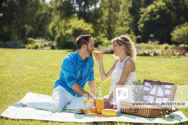 Happy couple having a picnic in park  pregnant woman