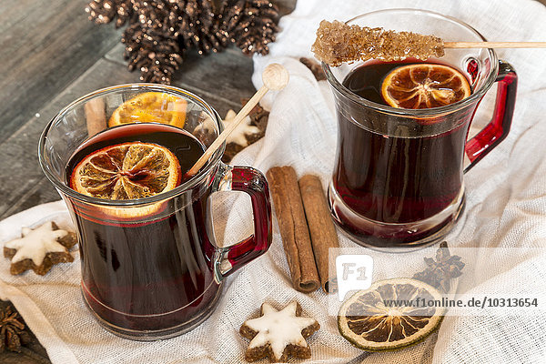 Glasses of mulled wine  orange slices and cinnamon stars on cloth and wooden tray