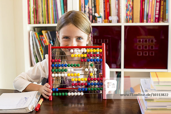 Smiling little girl sitting behind abacus