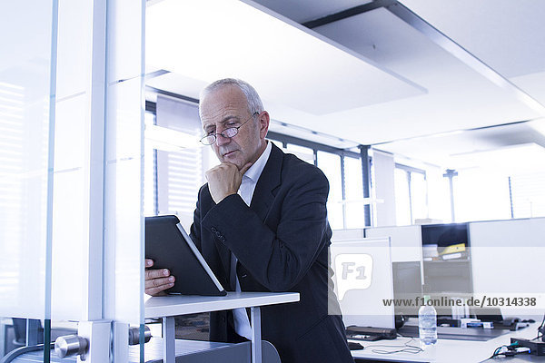 Geschäftsmann im Großraumbüro mit digitalem Tablett