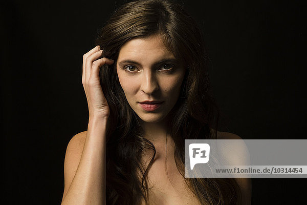 Portrait of brunette young woman in front of black background