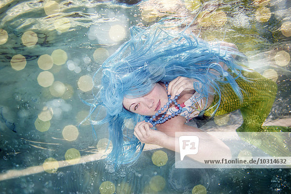 Junge Frau in der Verkleidung von Arielle  der kleinen Meerjungfrau  blaue Haare  unter Wasser