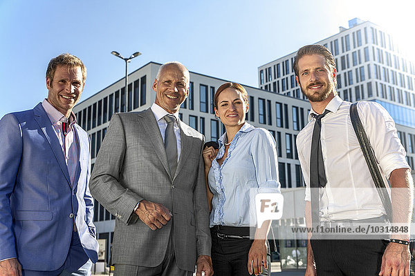 Vier lächelnde Geschäftsleute im Freien