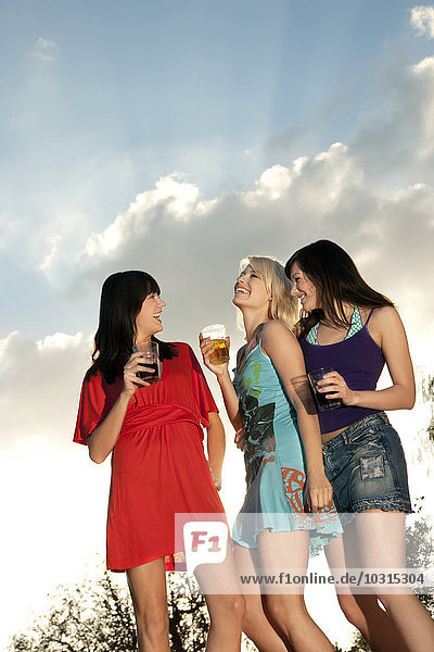 Drei glückliche junge Frauen feiern eine Party im Freien.