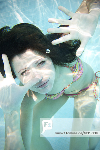 Portrait einer jungen Frau unter Wasser im Schwimmbad
