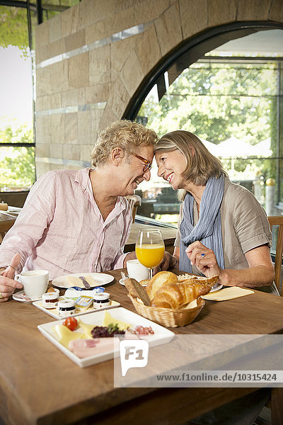 Lächelndes Seniorenpaar von Angesicht zu Angesicht beim Frühstück in einem Cafe