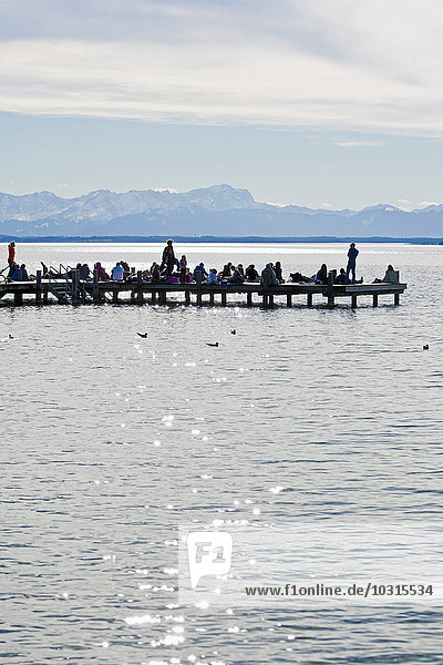 Deutschland  Bayern  Oberbayern  Starnberg  Starnberger See  Menschen am Steg  Bayerische Alpen und Zugspitze im Hintergrund