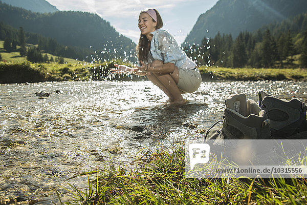 Austria  Tyrol  Tannheimer Tal  young female hiker refreshing in a brook