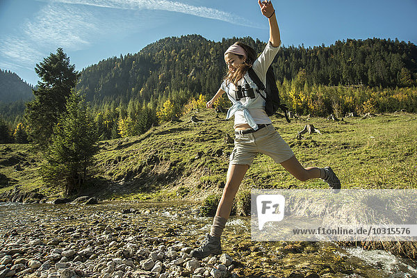 Austria  Tyrol  Tannheimer Tal  young female hiker crossing water