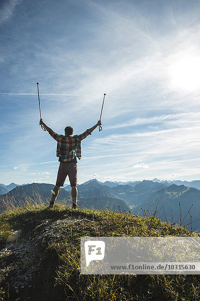 Österreich  Tirol  Tannheimer Tal  junger Mann jubelt auf den Berggipfel