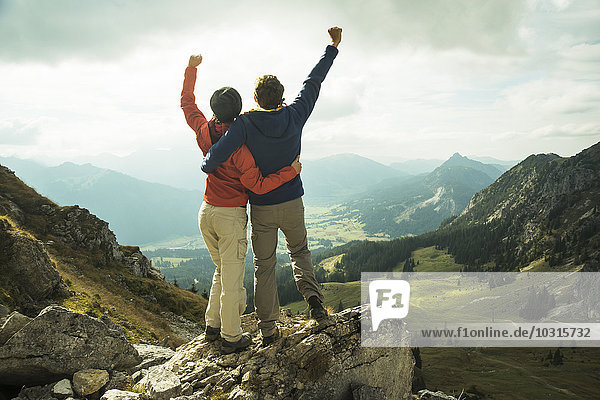 Österreich  Tirol  Tannheimer Tal  junges Paar jubelnd auf dem Berggipfel