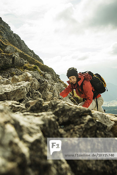 Austria  Tyrol  Tannheimer Tal  young woman climbing on rocks