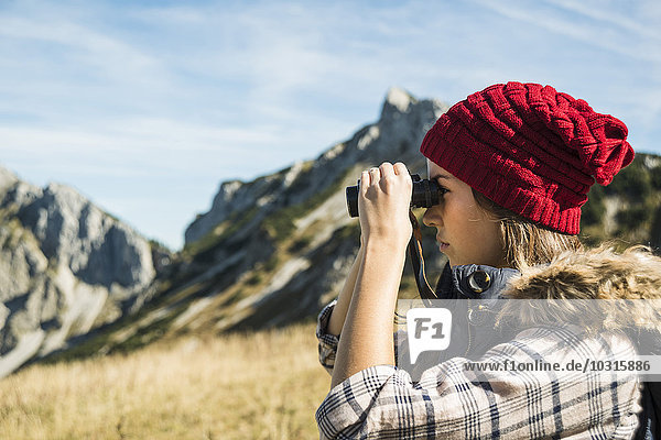 Austria  Tyrol  Tannheimer Tal  young woman looking through binocular