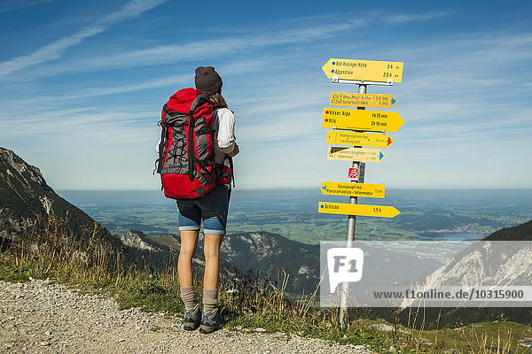Österreich  Tirol  Tannheimer Tal  junge Frau auf Wanderung am Wegweiser