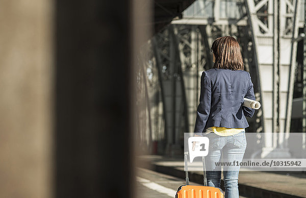 Junge Frau mit Gepäck am Bahnhof