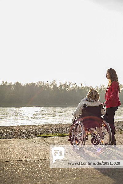 Enkelin  die ihrer Großmutter im Rollstuhl assistiert