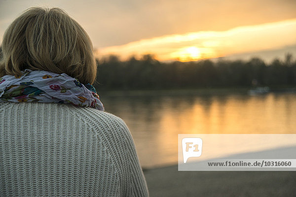 Senior woman watching sunset  back view