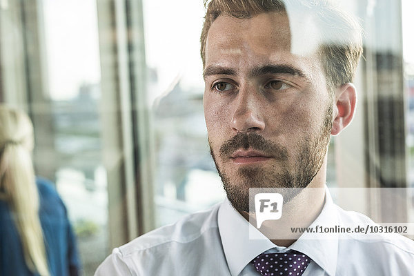 Serious young businessman looking out of window