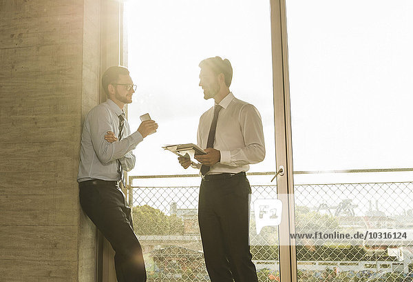 Zwei junge Geschäftsleute sprechen am Fenster im Büro