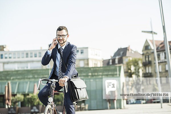 Young businessman riding bicycle  talking on the phone