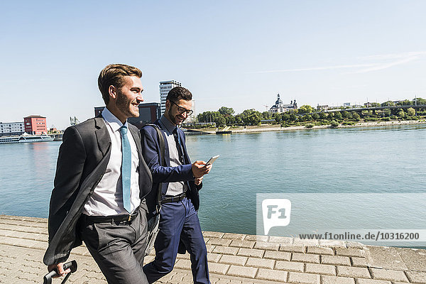 Two young businessmen on a business trip  walking by river